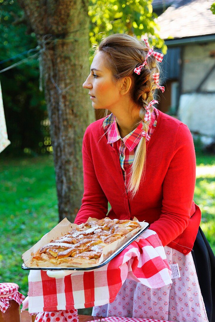 Frau mit frisch gebackenem Apfelkuchen im spätsommerlichen idyllischen Garten