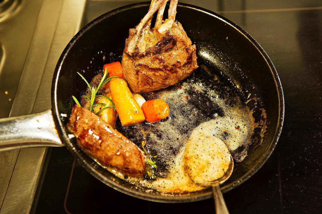 Venison with vegetables and herbs being fried in a pan