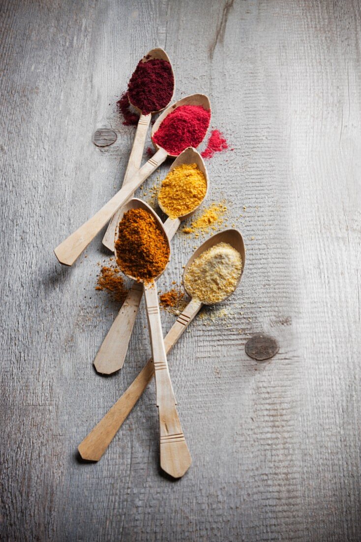 Five different types of fruit powder on wooden spoons