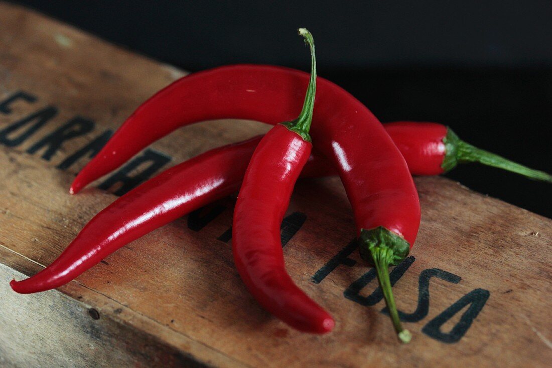 Three chilli peppers on a wooden crate