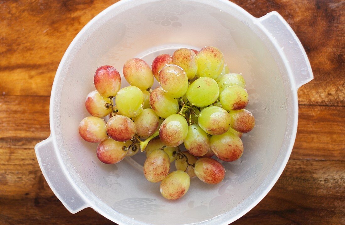 Fresh grapes in a plastic bowl (seen from above)