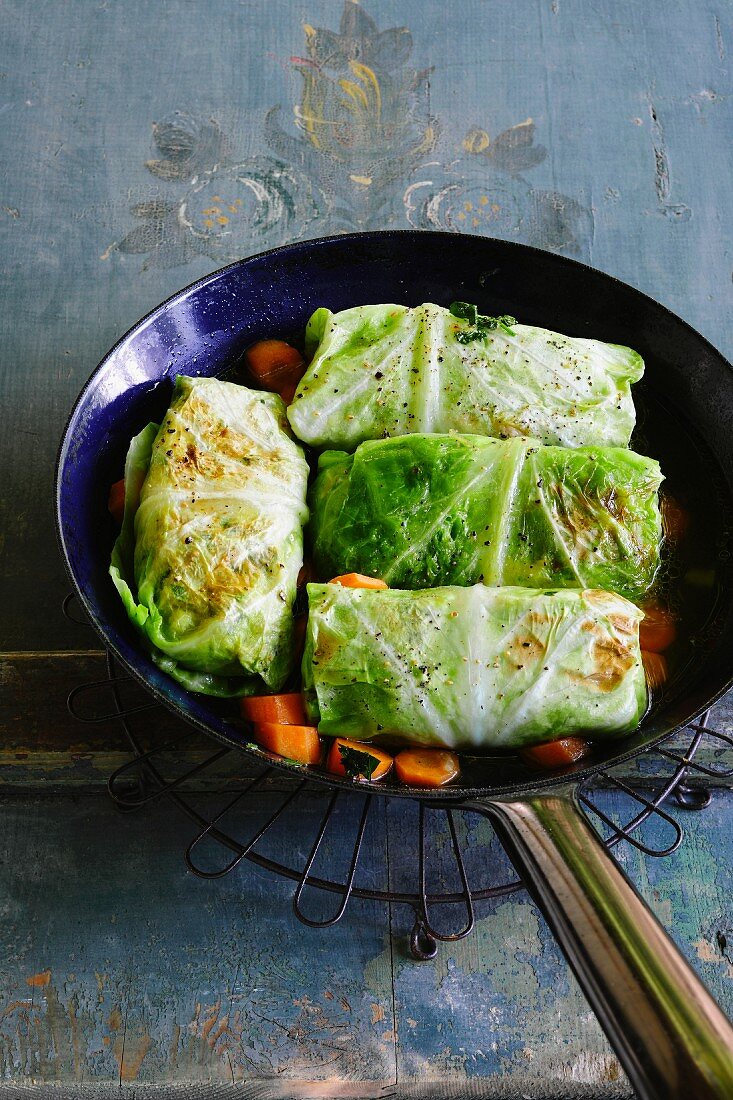 Cabbage parcels in a pan with steamed carrots