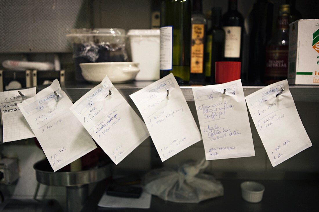 Orders on pieces of paper in a restaurant kitchen