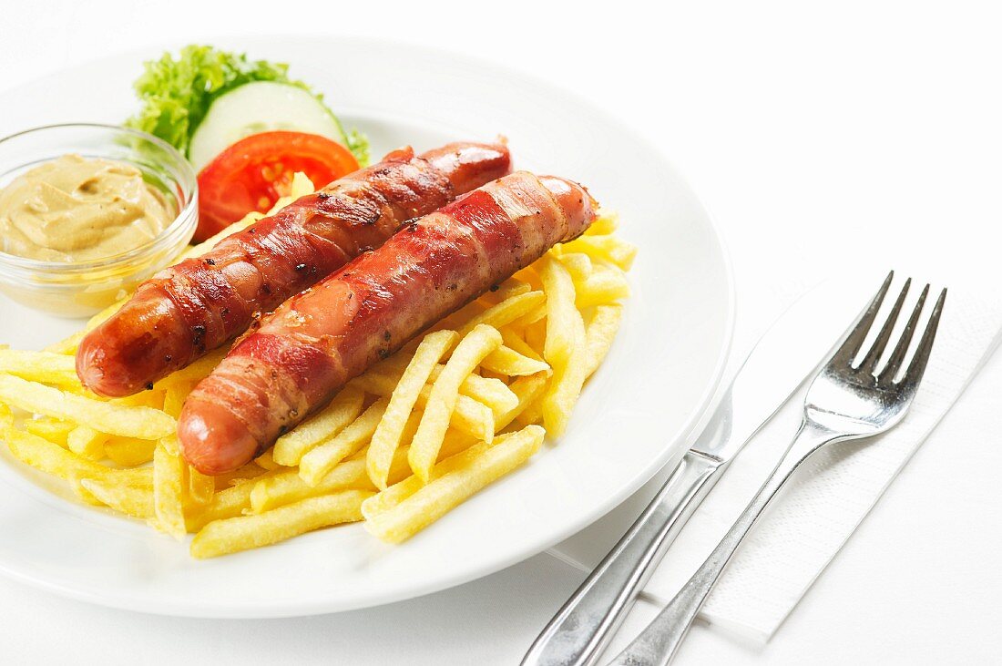 Grilled sausages wrapped in bacon with mustard and chips