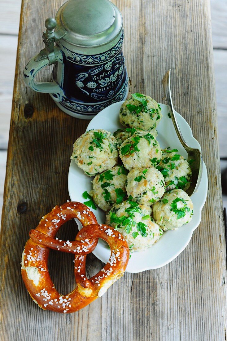 Semmelknödel mit Petersilie, daneben Breze und rustikaler Bierkrug