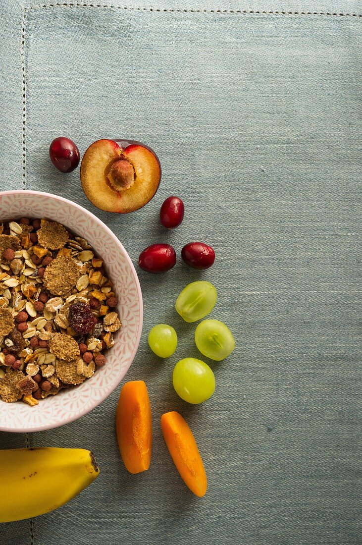 Müsli im Schälchen, daneben frische Früchte