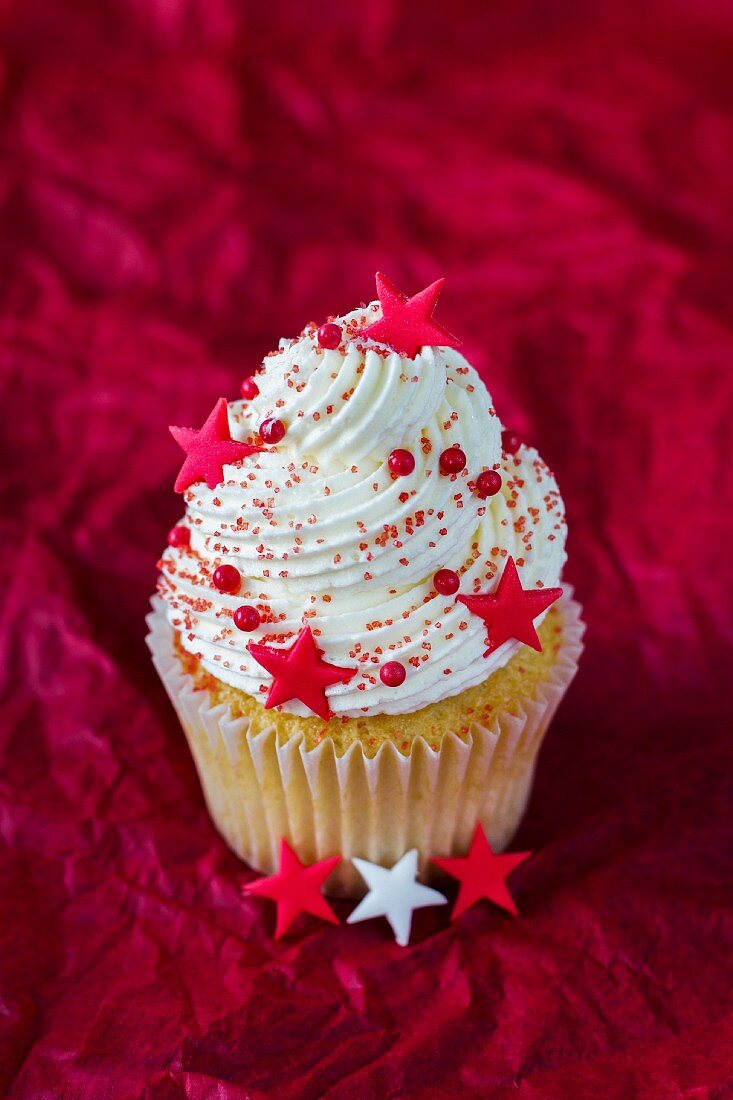 An almond cupcake topped with cream and decorated with stars