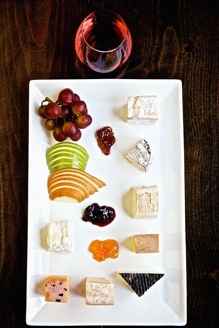 A cheese platter with fruit, jam and wine