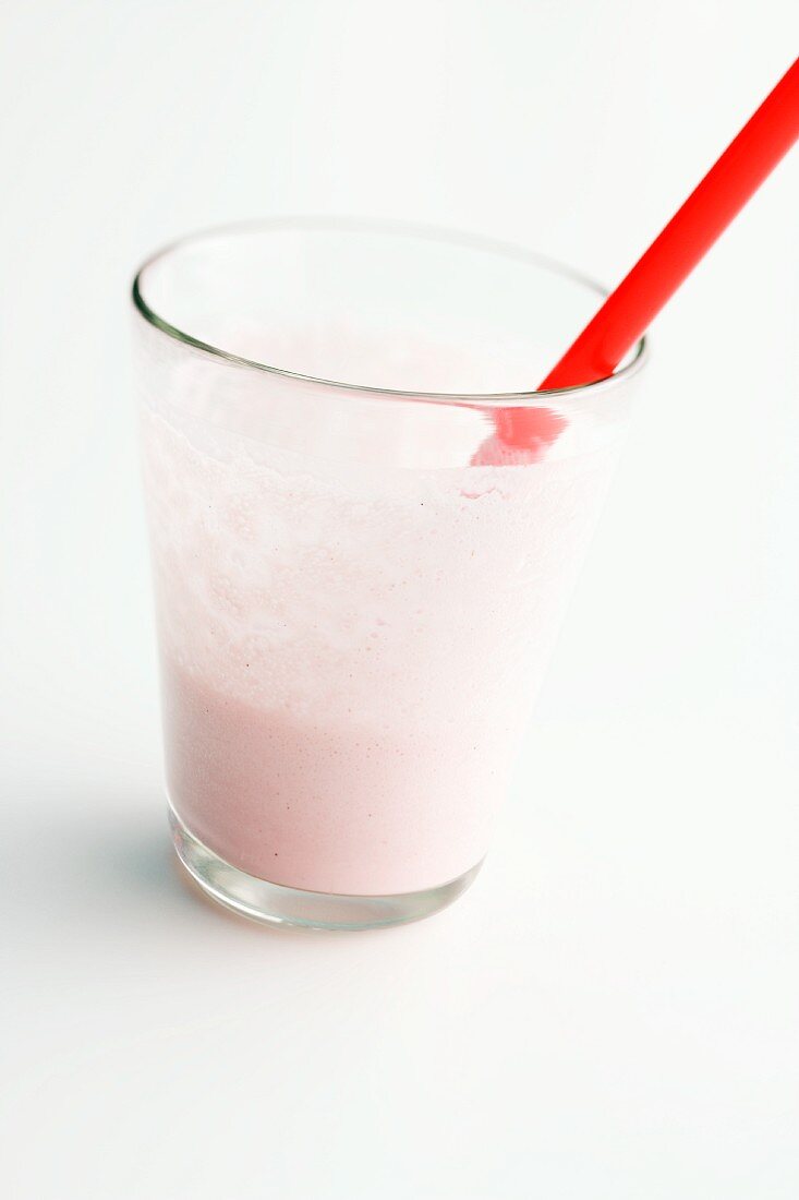 The remains of a strawberry milkshake in a glass with a straw