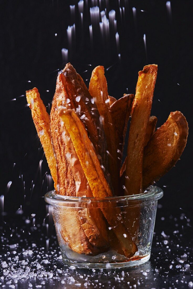 A glass of chips being salted