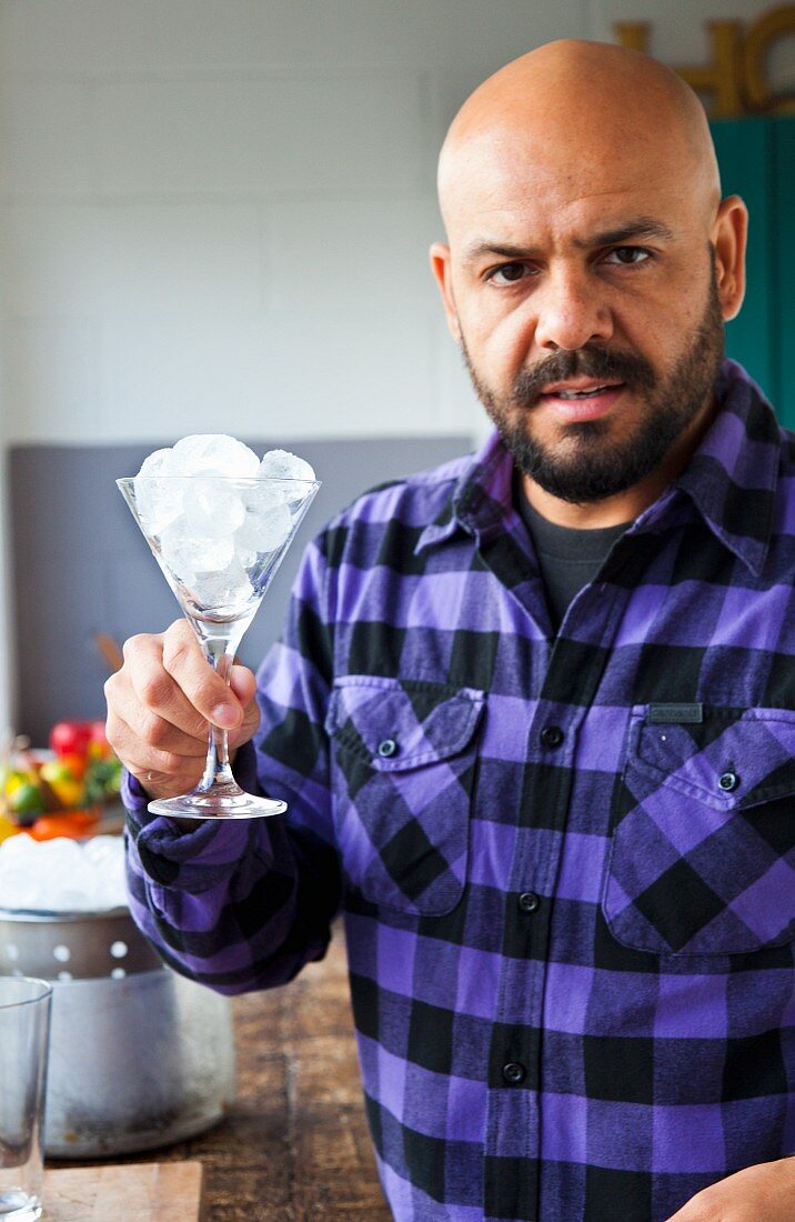 A barkeeper holding a cocktail glass filled with ice cubes