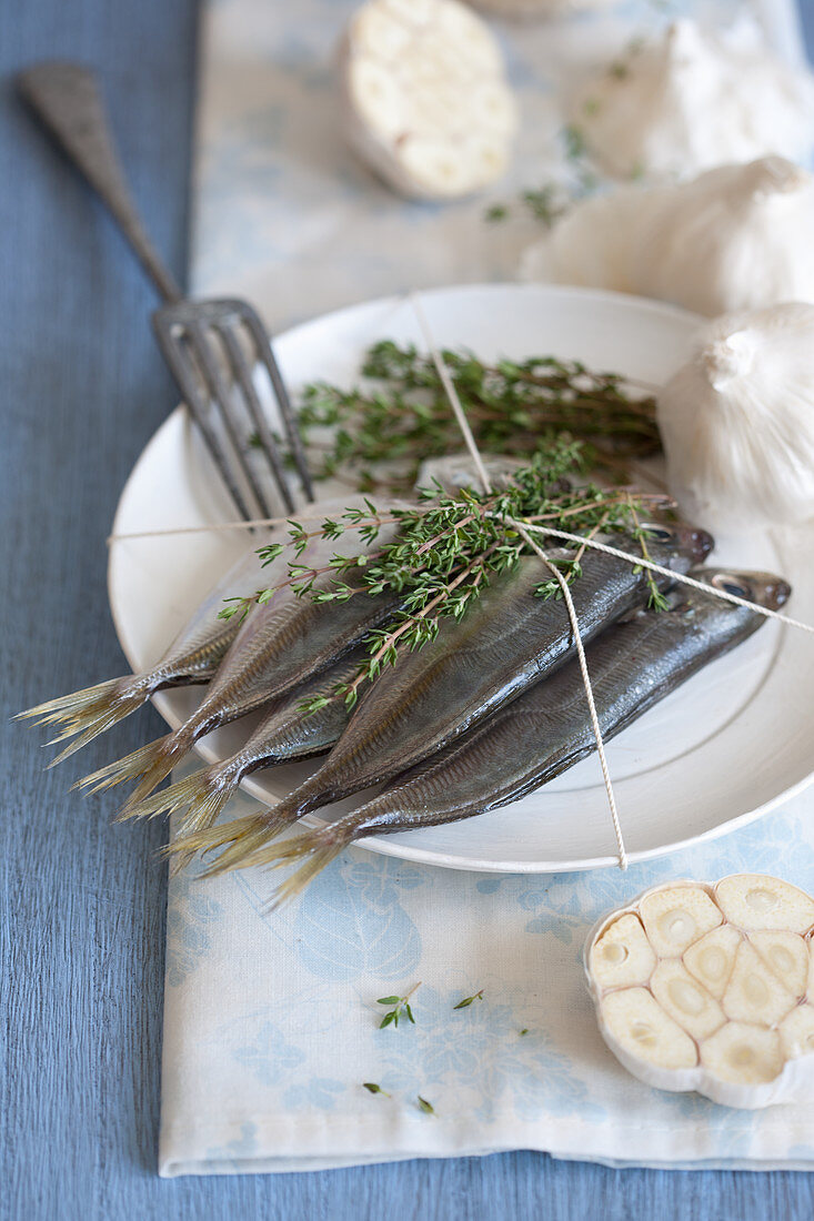 Raw sardines on a plate with thyme and garlic