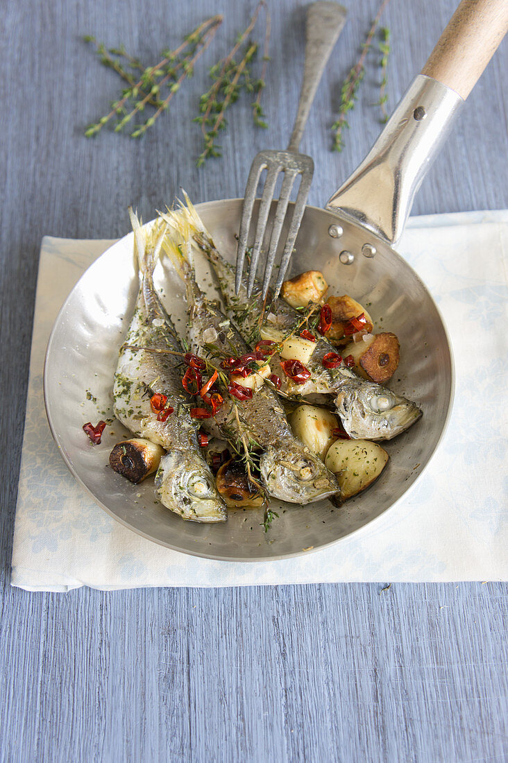 Fried sardines with garlic, thyme and chilli in a pan