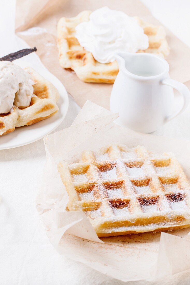 Belgian waffles served with whipped cream, ice cream, icing sugar and a jug of milk