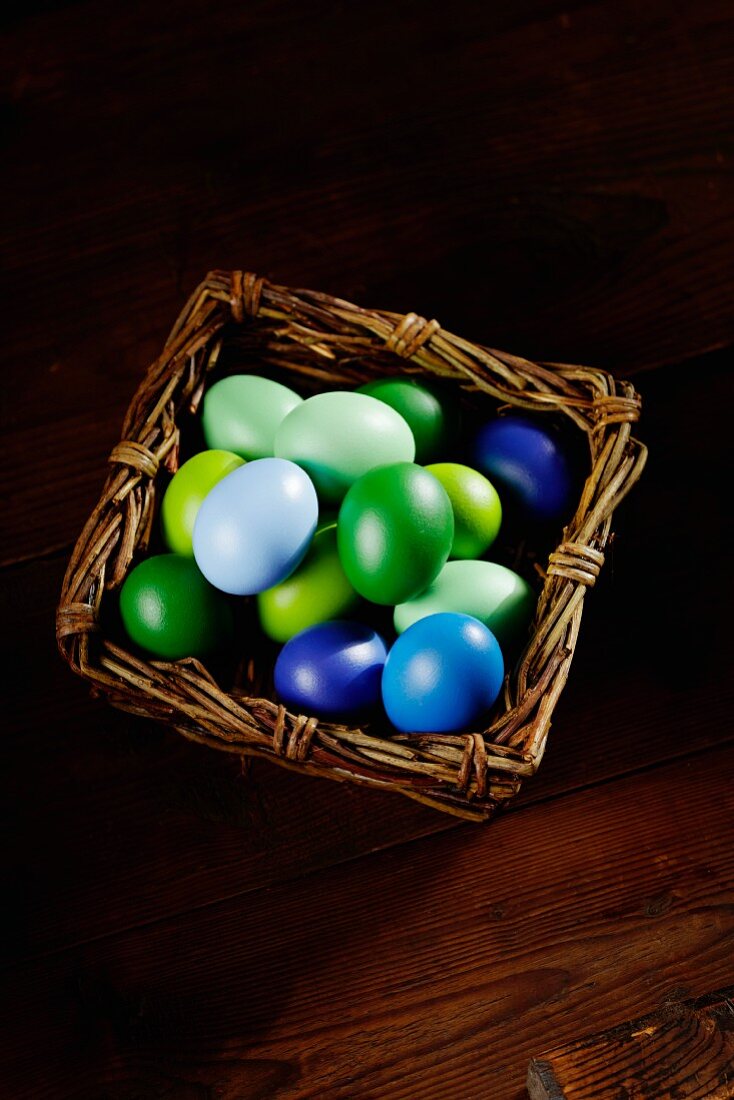 Blue and green Easter eggs in a wicker basket