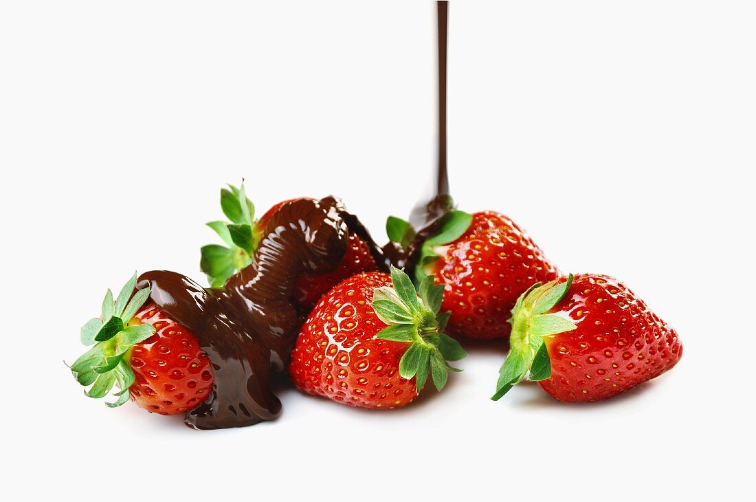 Schokolade fliesst auf frische Erdbeeren