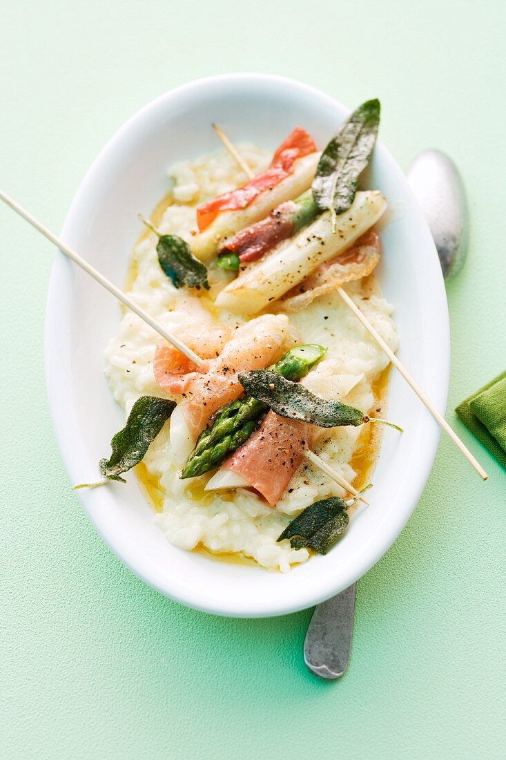 Asparagus skewers with ham and sage on a bed of creamy risotto