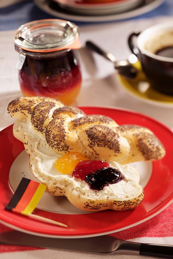 A poppyseed roll spread with butter and various types of jam