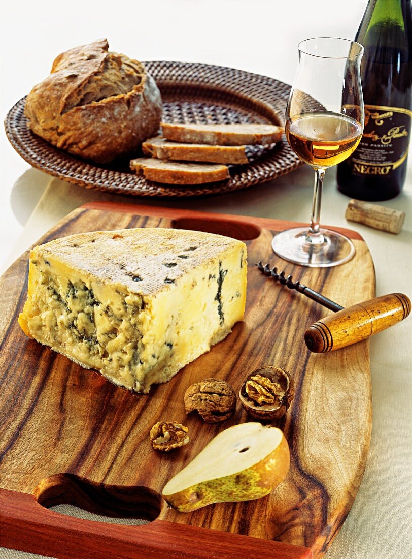 An arrangement of cheese with white wine, bread, nuts and pears