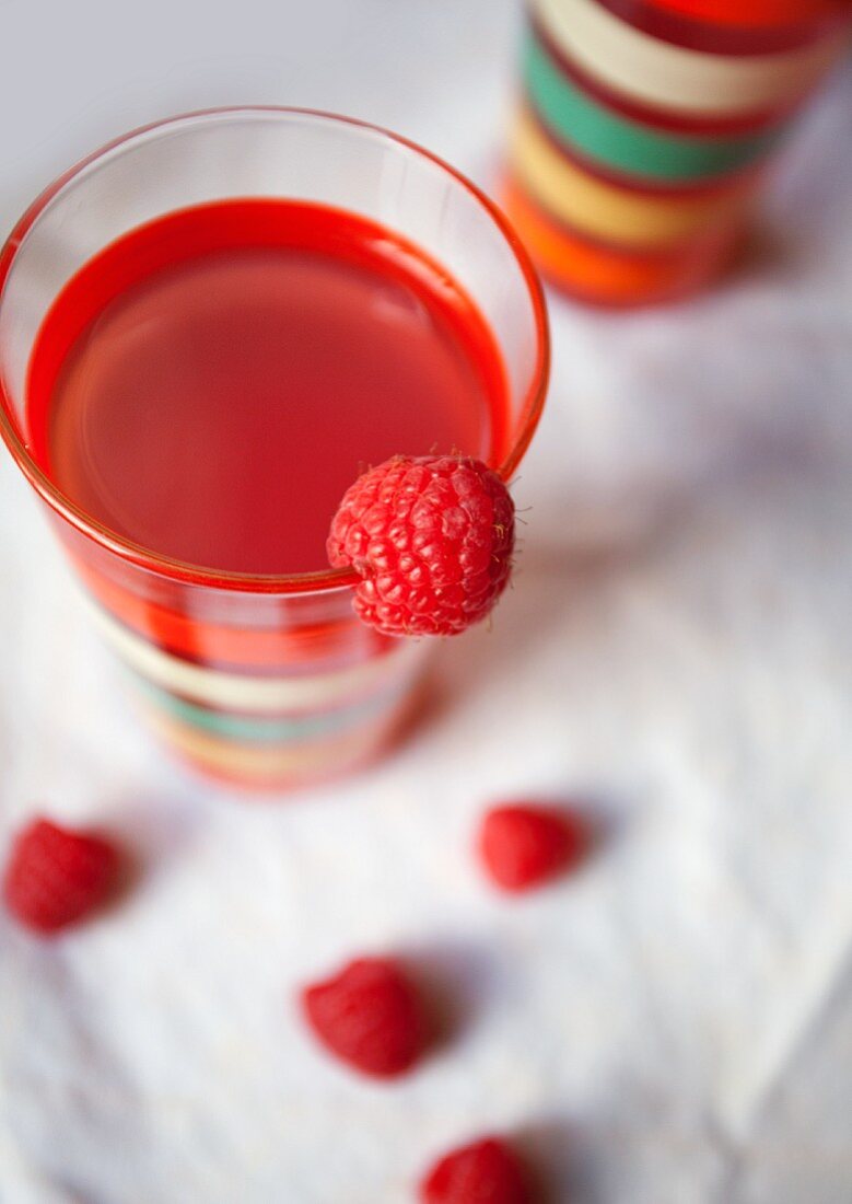 A glass of raspberry juice and fresh raspberries