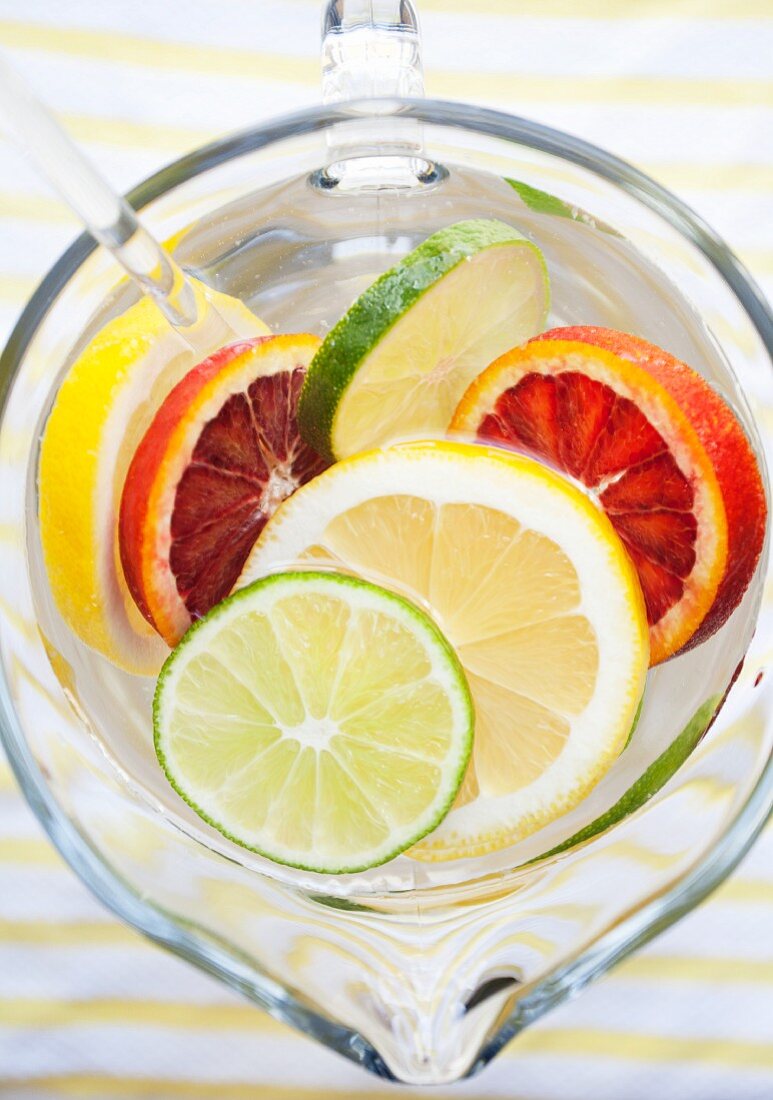 Various different citrus fruit slices in a jug of water