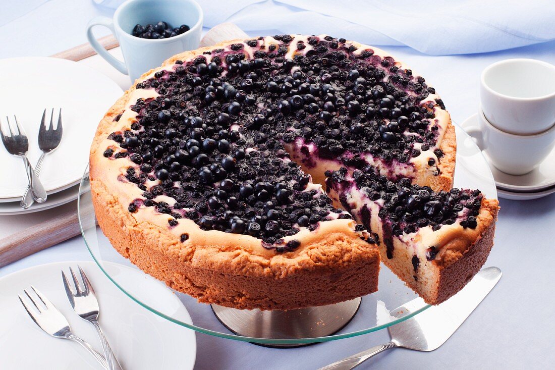 Slice of Blueberry Cheesecake on a Plate, Whole Cheesecake with Slice Removed