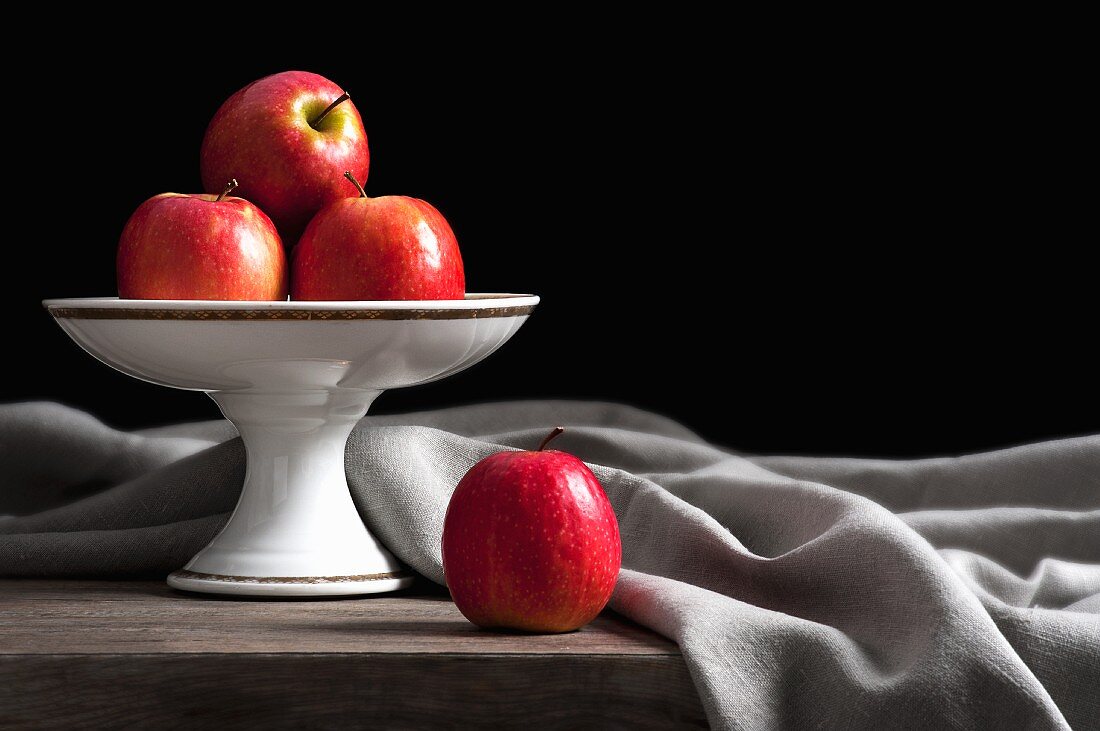 Apples on a cake stand with an elegantly draped cloth