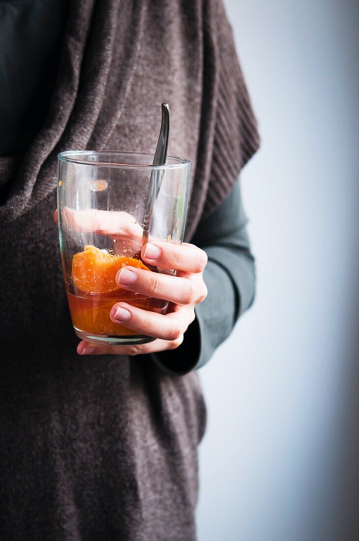 A woman holding a glass of peach compote
