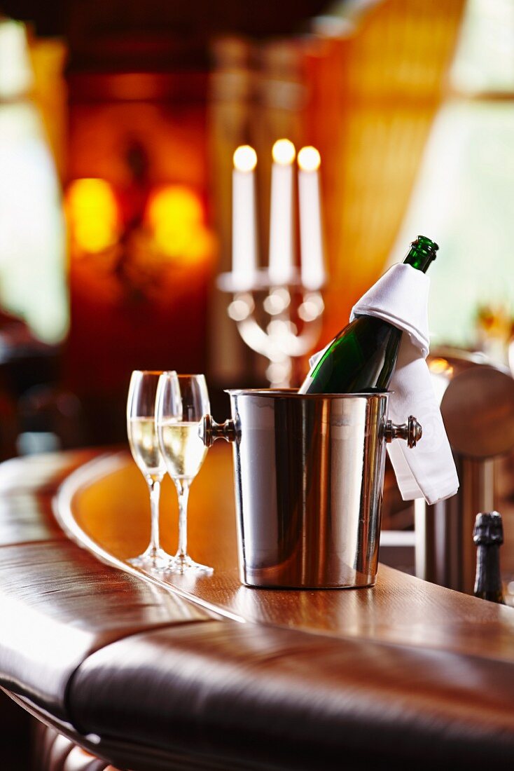 A bottle of champagne and champagne glasses on a bar