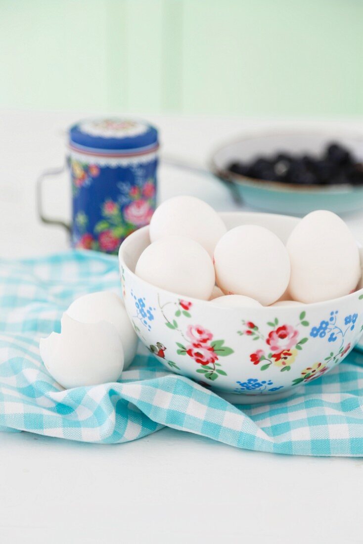 Eggs in a floral porcelain bowl on a checked napkin with egg shells next to it