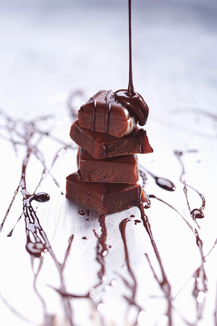 Chocolate sauce being poured over a stack of chocolate