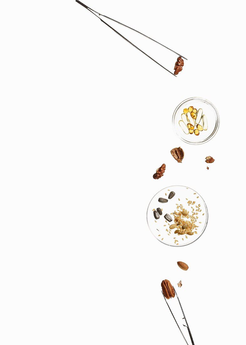 Nuts, seeds and pills in glass dishes and in tweezers