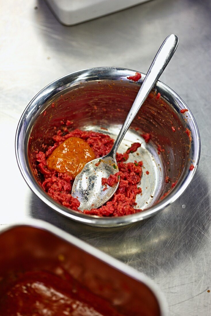 Minced meat with mustard in a metal bowl