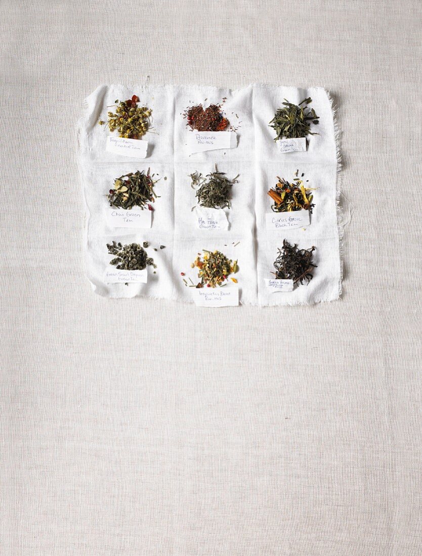 Verschiedene Teesorten mit Namensschild auf weißem Tuch