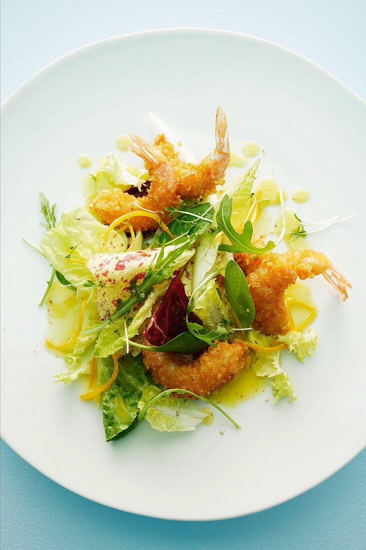 A mixed leaf salad with baked king prawns and an orange dressing
