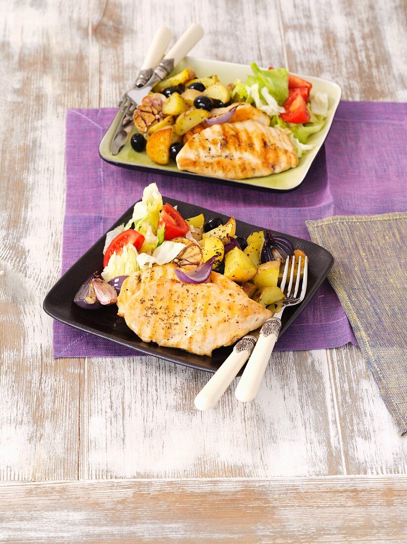 Grilled chicken breast with baked potatoes, garlic and red onions