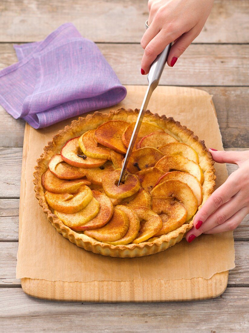 An apple tart with cinnamon being sliced