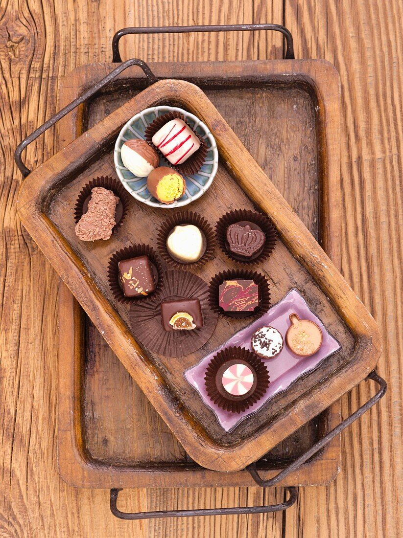 Various chocolate pralines on a wooden tray
