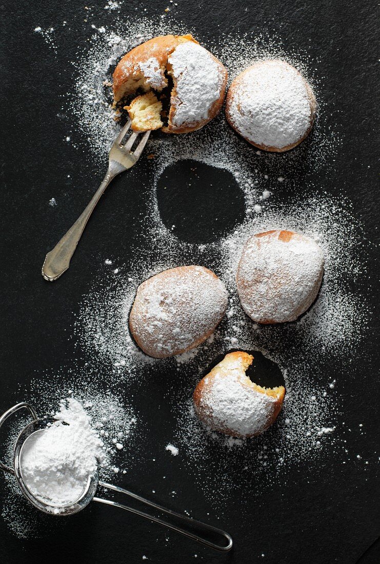 Doughnuts with icing sugar on a black surface