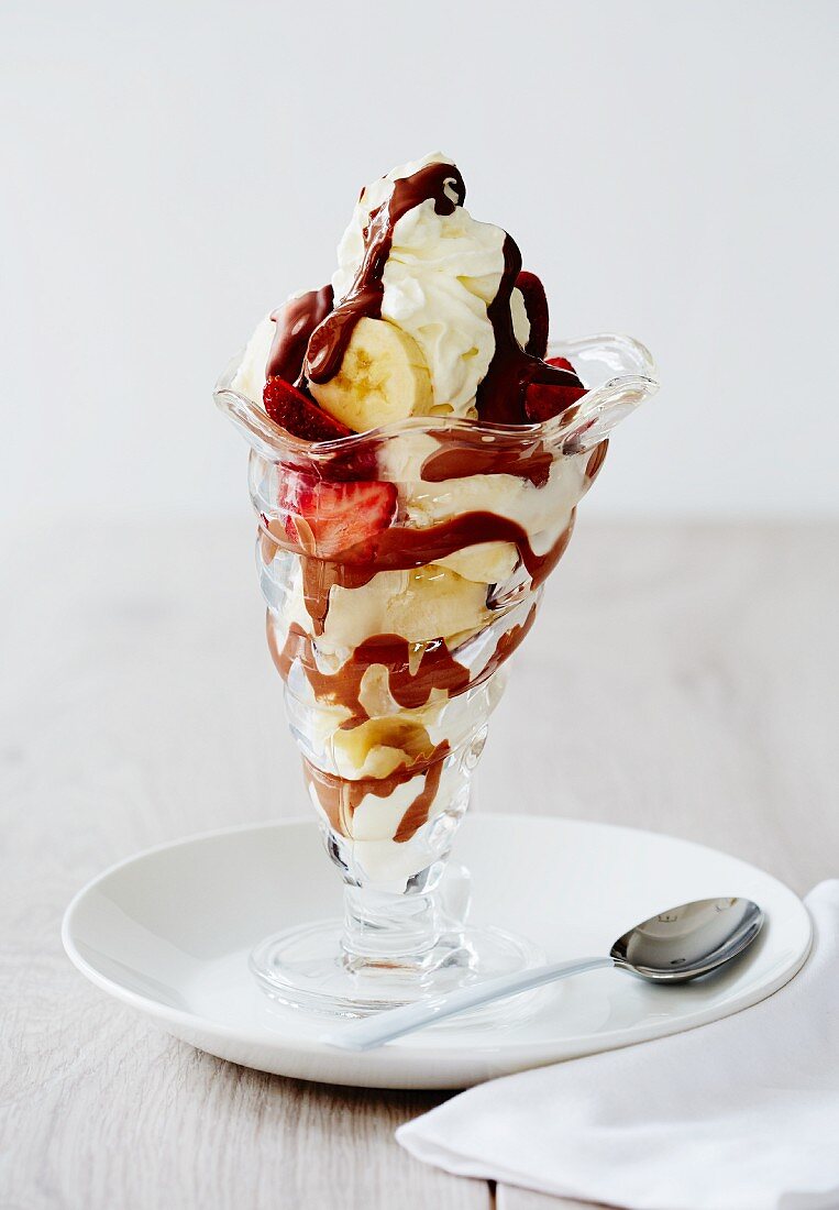 An ice cream sundae with banana, strawberries and chocolate sauce
