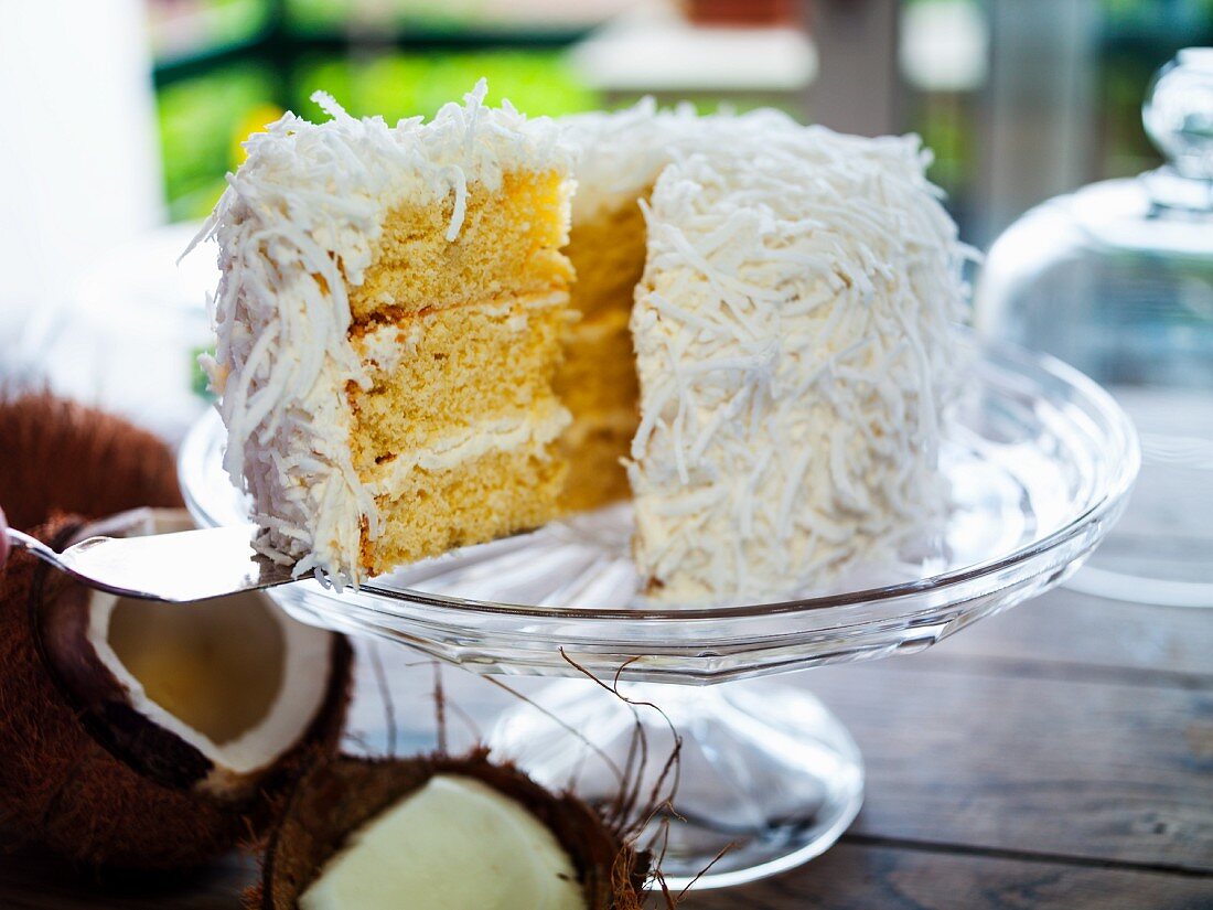A sliced coconut cake on a cake stand