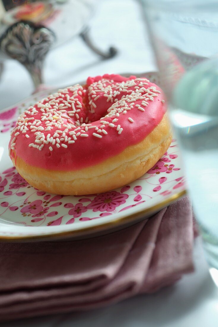 A doughnut decorated with pink icing and sprinkles