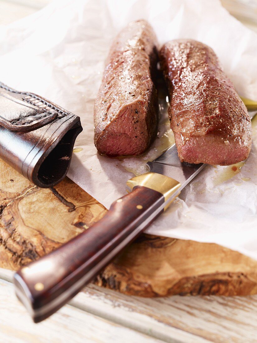 Saddle of venison with a knife on a wooden board