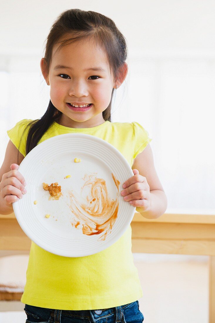 Mädchen zeigt Teller mit Essensresten