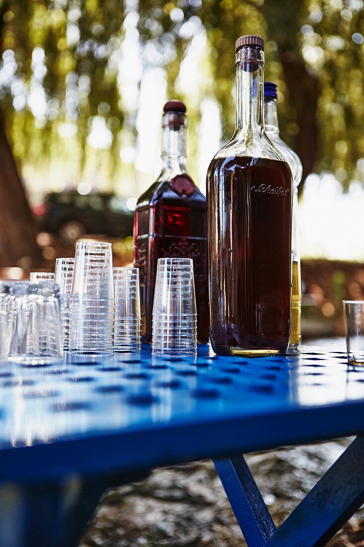 Mastika (Schnaps, Kroatien) in Flaschen mit Gläsern auf Tisch im Freien