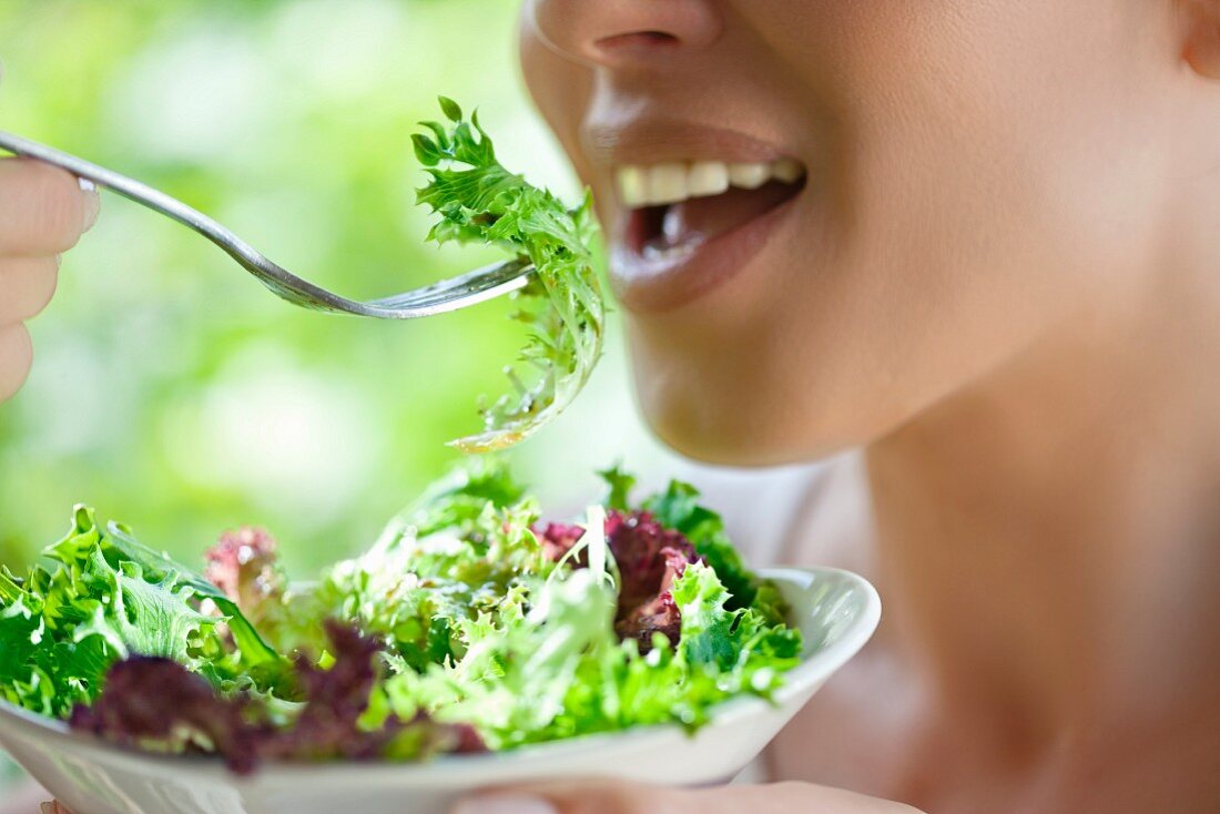 A young woman eating a fresh salad