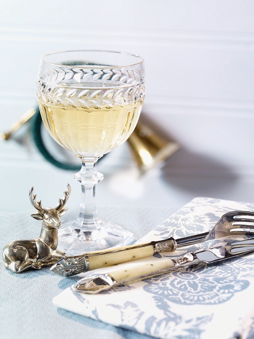 Ein Glas Weißwein, Besteck und Serviette