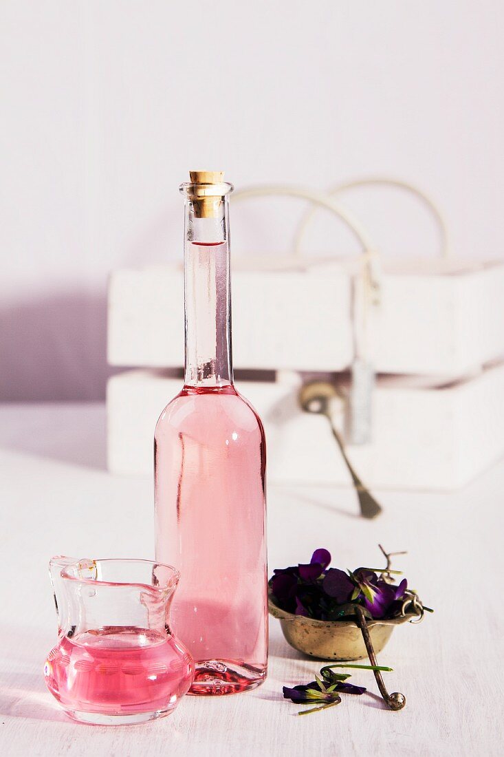Violet vinegar in a bottle and a small glass jug