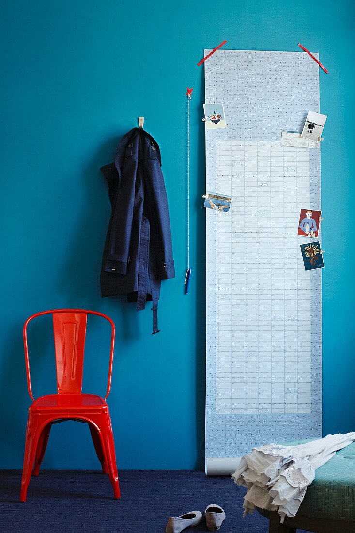 Postcards pegged to roll of wallpaper stuck on blue wall with sticky tape