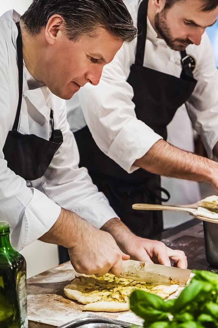 A chef slicing a pizza in a restaurant kitchen